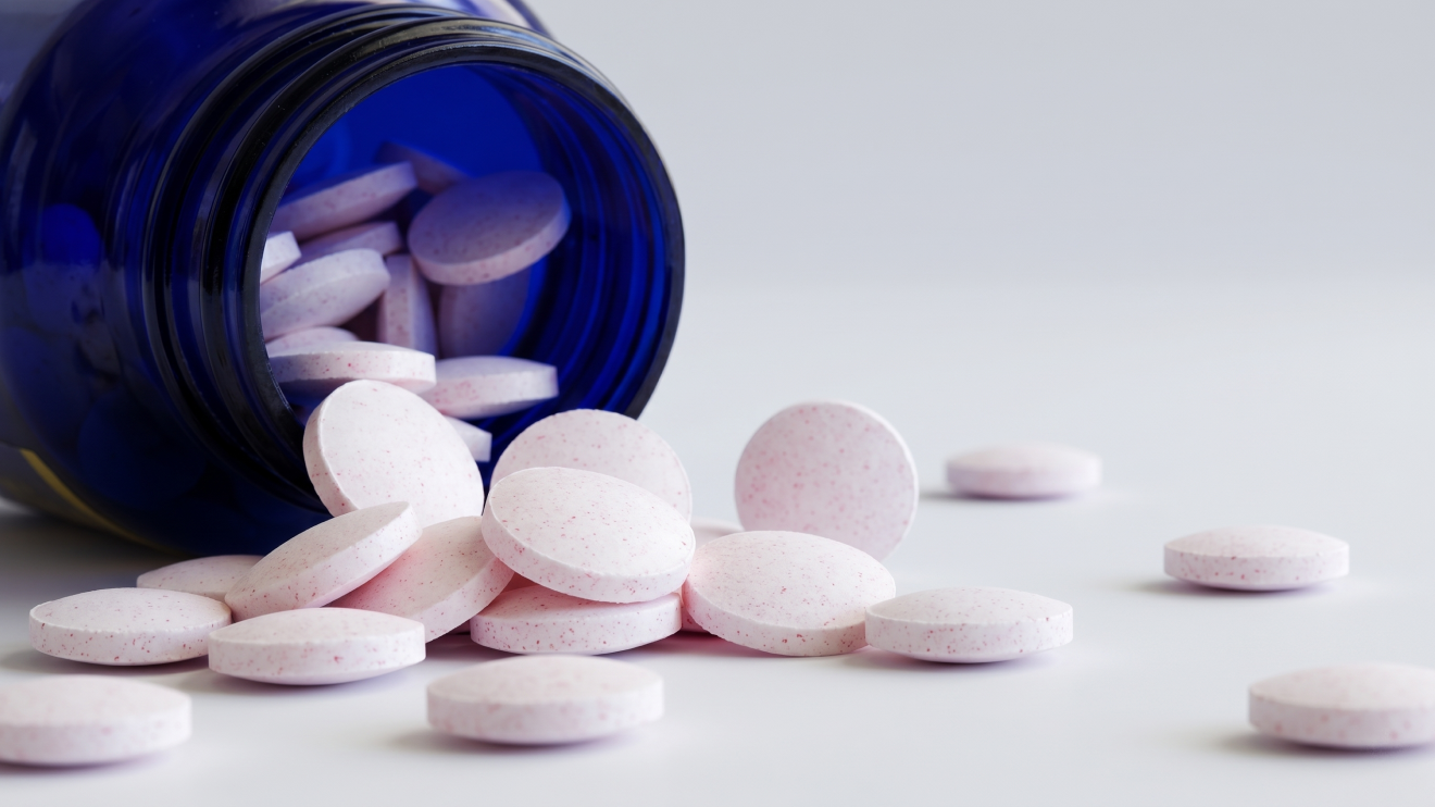 10 Sleep Aids That Actually Work: Science-Backed Options For Better Rest 2 A Spilled Bottle Of Speckled Pink Tablets Of Melatonin, Coming Out Of A Blue Bottle.