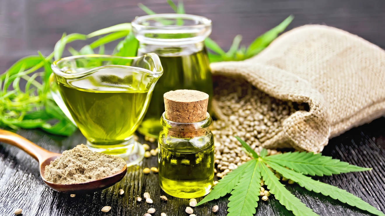 10 Sleep Aids That Actually Work: Science-Backed Options For Better Rest 4 A Still Life Arrangement Of Cannabidiol (Cbd) Products On A Dark Wooden Table. The Composition Includes Golden Cbd Oil In A Small Corked Bottle And A Glass Pitcher, A Wooden Spoon Holding A Mound Of Greenish-Brown Powder, A Rustic Burlap Sack Spilling Hemp Seeds, And Fresh Green Cannabis Leaves Scattered In The Foreground.