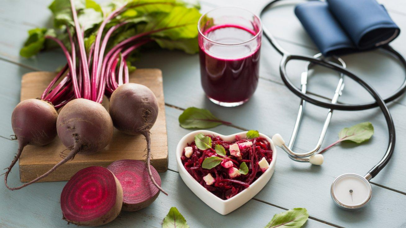 7 Beetroot Supplement Benefits You Should Know Before Taking 3 Fresh Beets, Beet Juice, And A Heart-Shaped Beet Salad Arranged Beside A Stethoscope And Blood Pressure Cuff On A Pale Blue Wooden Table, Illustrating The Connection Between Beetroot Nutrition, Circulation, And Heart Health.