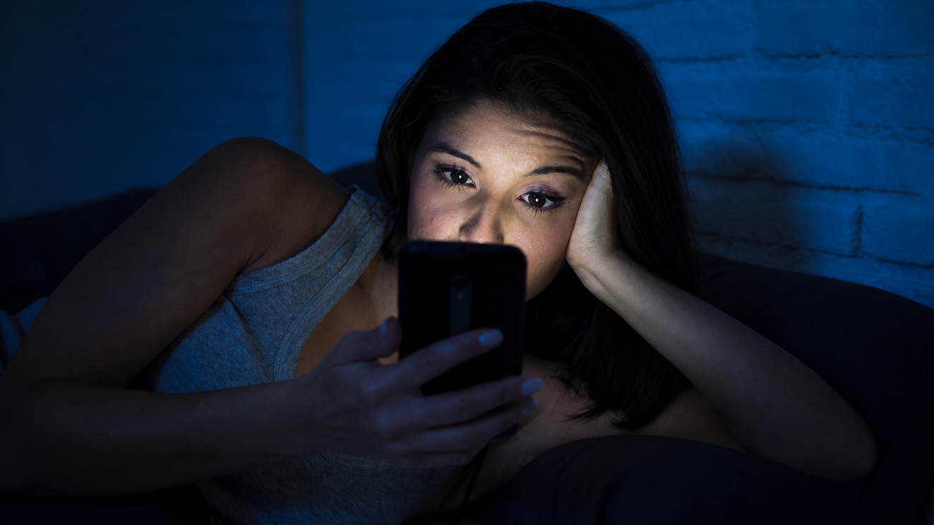 Why Your Skin Looks Tired: 9 Hidden Causes &Amp; Quick Fixes 2 Woman Lying Awake In Bed At Night, Distracted By Her Phone’s Blue Light Instead Of Sleeping, Suggesting Sleep Deficit That May Leave Skin Looking Tired, Dull, And Less Healthy.