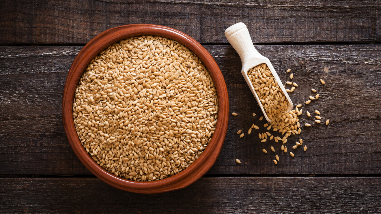 10 Foods To Eat More Often To Support Healthy Aging 7 Overhead View Of A Terracotta Bowl And Wooden Scoop Filled With Golden Wheat Grains On A Rustic Dark Wooden Table, With Loose Grains Scattered Nearby.